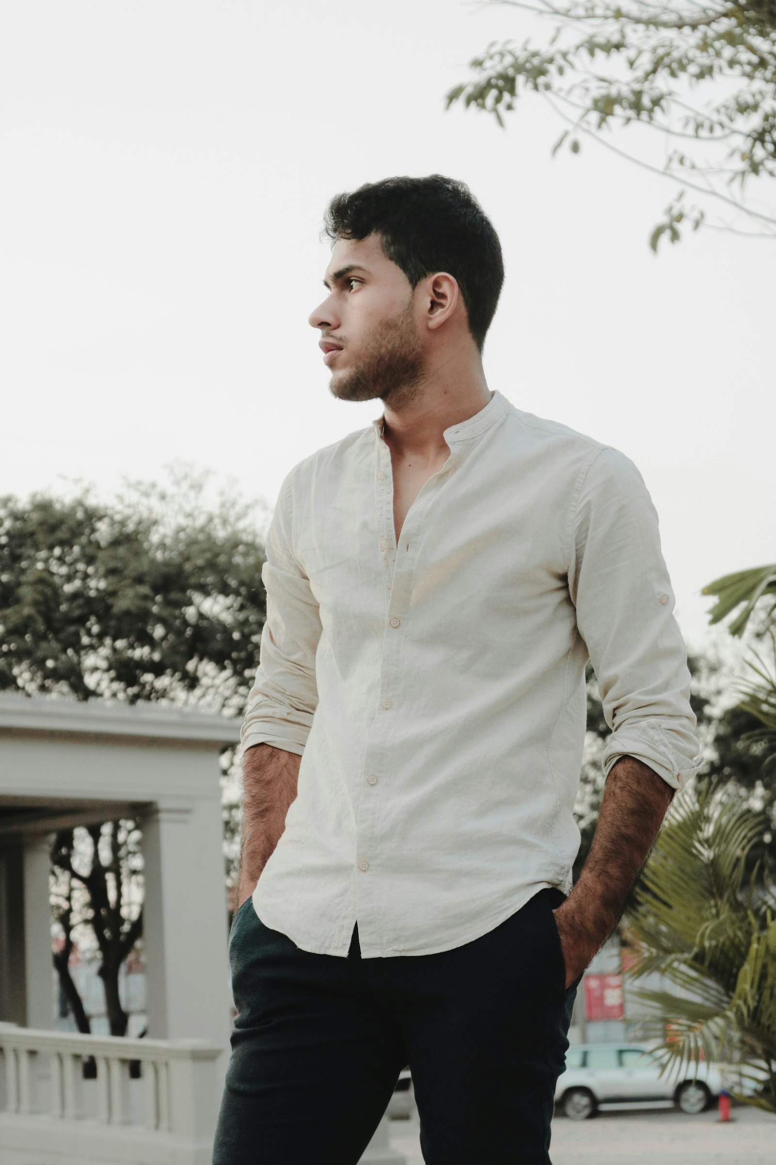 Man in a cream mandarin-collar linen shirt with dark trousers