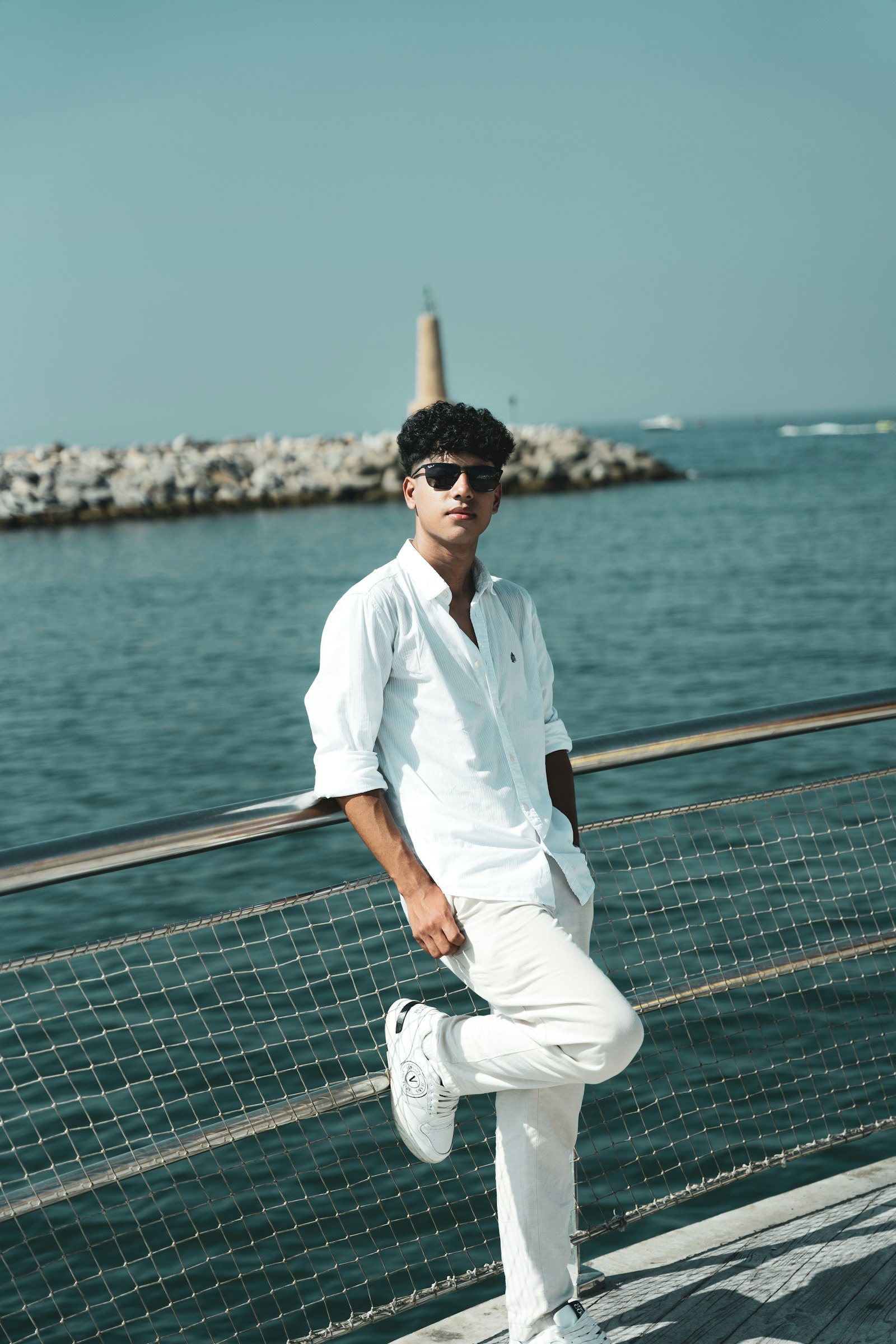 Man in a crisp white linen shirt and trousers by the sea