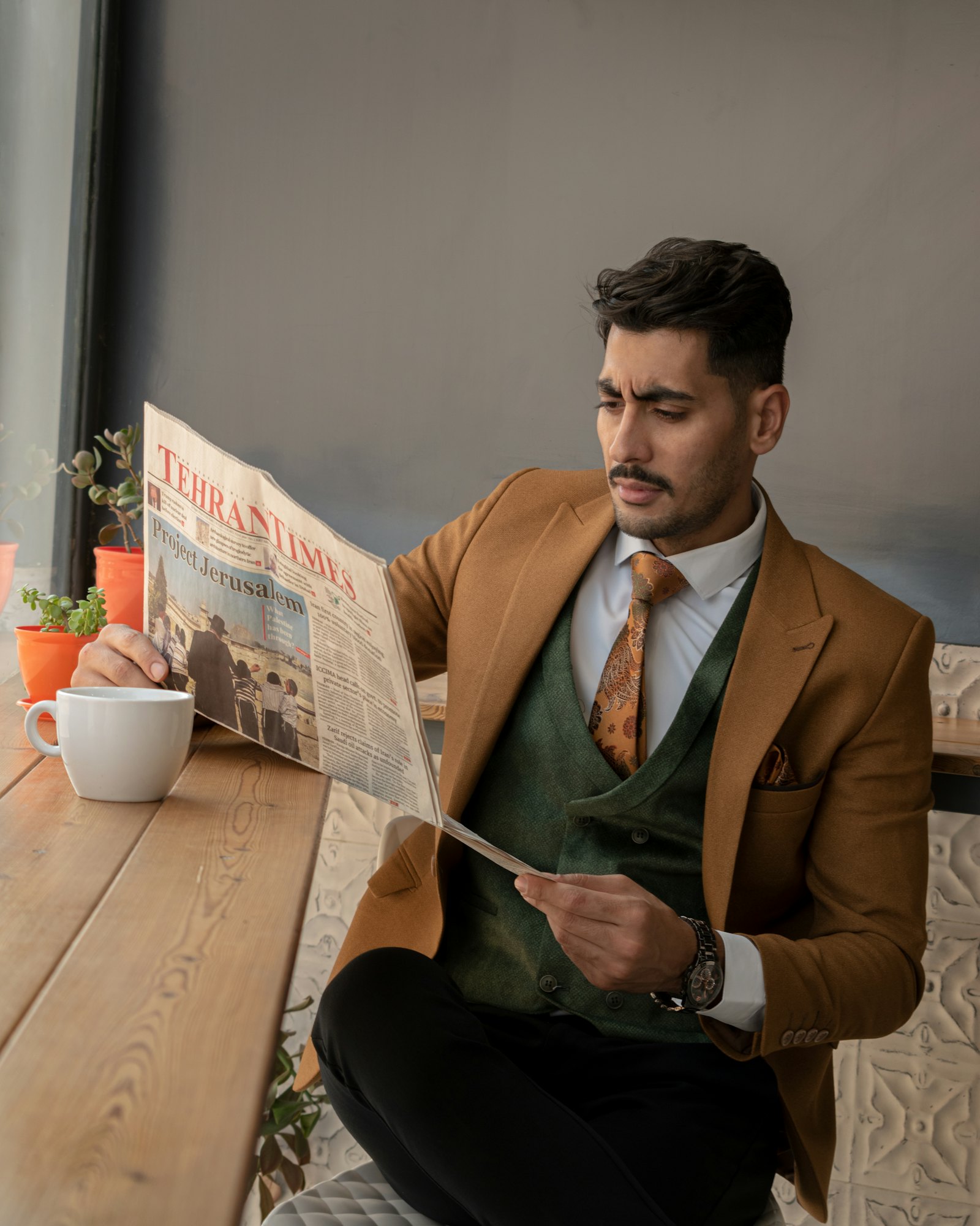Man in a camel jacket layered over a green waistcoat