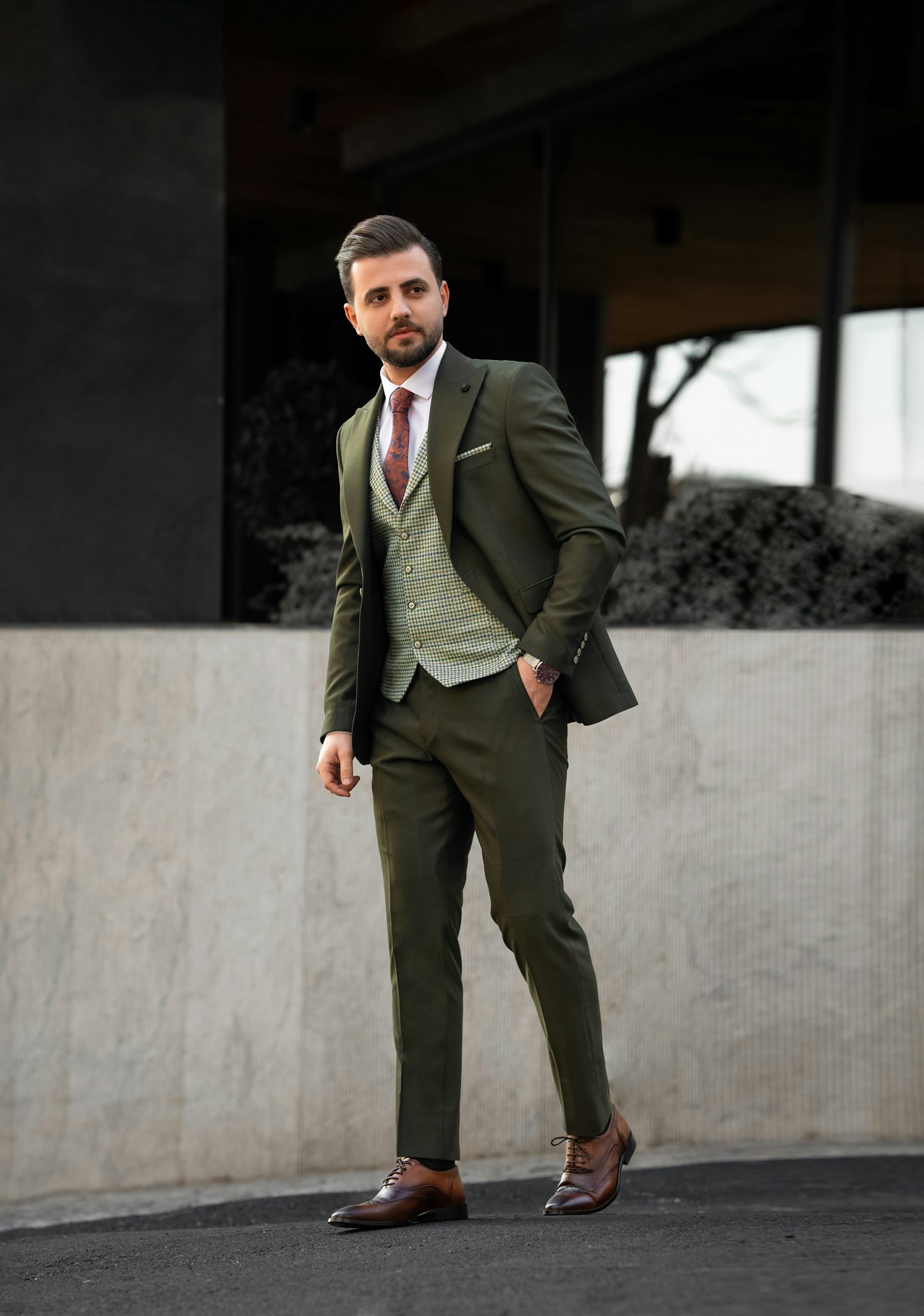 Man in an olive green three-piece wool suit with a checked waistcoat